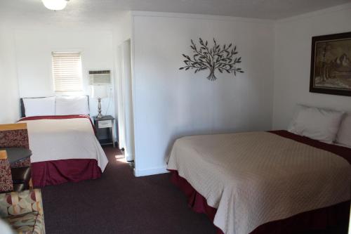 a hotel room with two beds and a clock on the wall at Chalet Motel - Affordable Stay in Central Bend in Bend