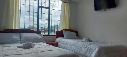 a bedroom with two beds and a large window at S&C HOTEL in Sogamoso