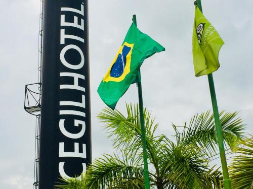 two flags on poles next to a hotel sign at Cegil Hotel Boulevard in Resende