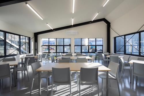 a cafeteria with tables and chairs and windows at Harvest Park Studios Accommodation in Cromwell