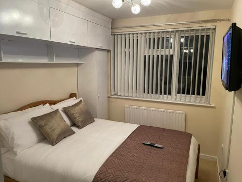 1 dormitorio con cama, ventana y TV en Elegant Devon, en Luton