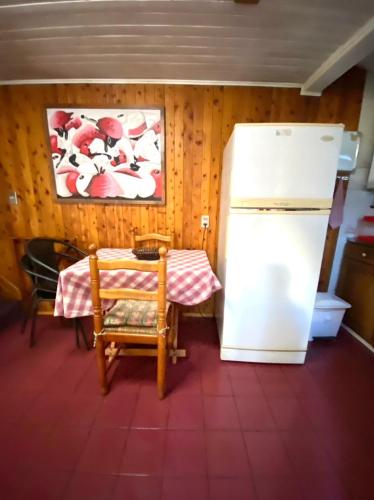 a kitchen with a table and a refrigerator at Torres Del Sur Cabañas & Hostal in Villarrica