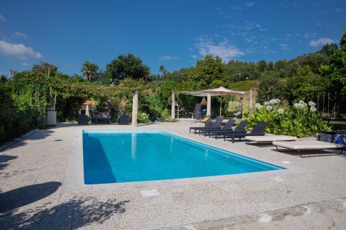 a swimming pool with chairs and a gazebo at Casa de Cardido in Guimarães
