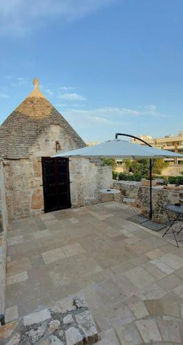 a patio with a white umbrella and a building at B&b I Trulli dei Desideri in Alberobello