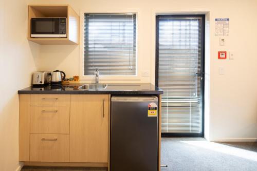 a kitchen with a sink and a refrigerator at Harvest Park Studios Accommodation in Cromwell
