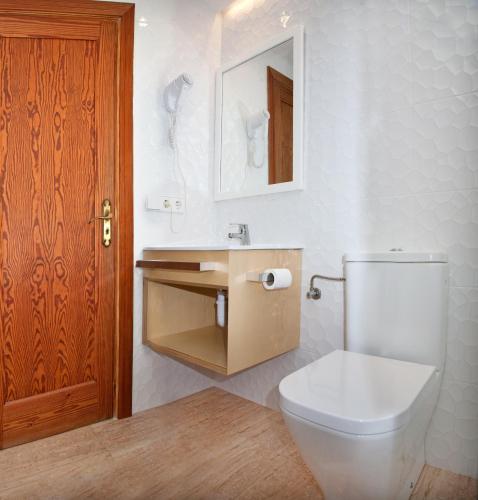 a bathroom with a white toilet and a wooden door at Mar Blau in Port d'Alcudia