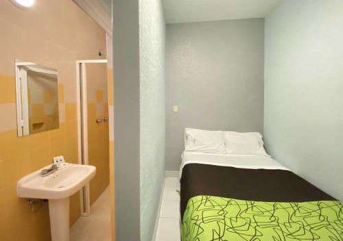 een kleine kamer met een bed en een wastafel bij HOTEL GRAN VIA CENTRAL in Mexico-Stad