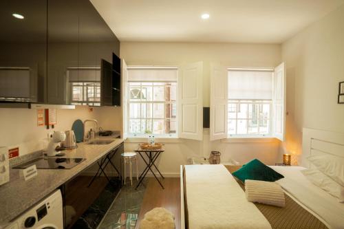 uma cozinha com armários brancos e um sofá em Alojamento 5 de Outubro em Amarante