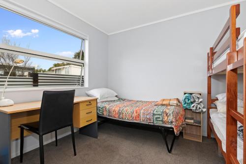 a bedroom with a desk and a bed and a window at Pohutukawa Peace - Mangawhai Holiday Home in Mangawhai