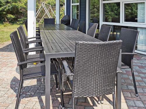 a wooden table and chairs on a patio at 12 person holiday home in V ggerl se in Marielyst