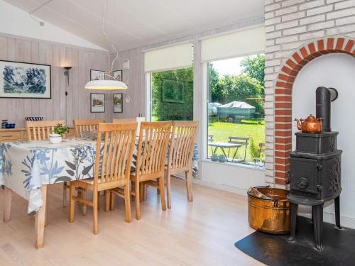 uma sala de jantar com uma mesa e um fogão a lenha em Three-Bedroom Holiday home in Glesborg 33 em Bønnerup