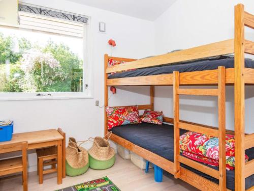 a bedroom with bunk beds and a table and a window at Three-Bedroom Holiday home in Glesborg 33 in Bønnerup