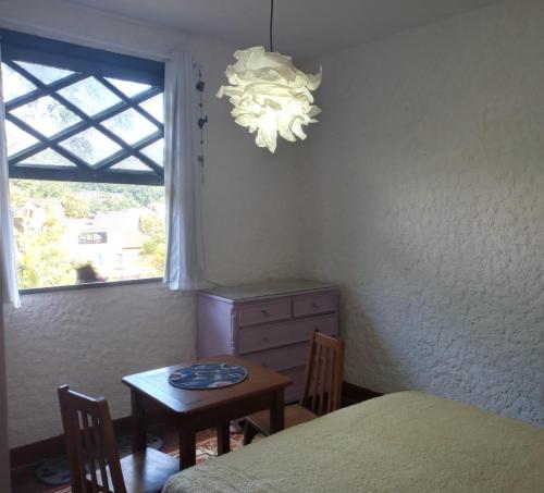a bedroom with a table and a window and a chandelier at Criatividade na Serra in Petrópolis