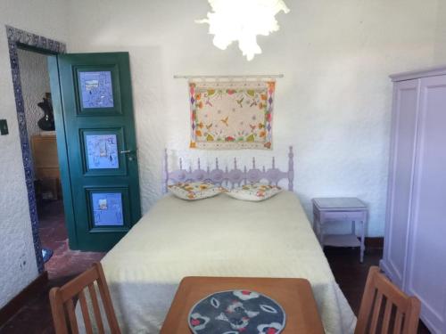 a bedroom with a bed with a table and two green doors at Criatividade na Serra in Petrópolis
