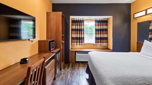 a hotel room with a bed and a flat screen tv at SureStay Plus Hotel by Best Western Keyser in Keyser
