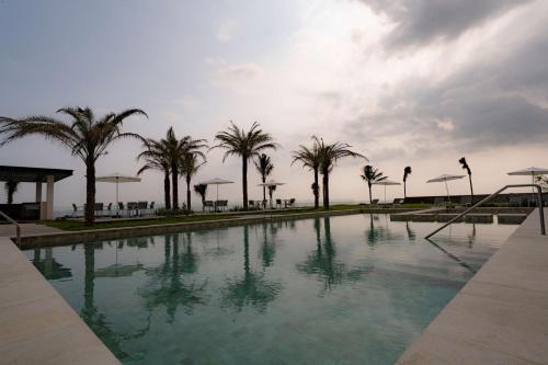 uma piscina com palmeiras e um céu nublado em Best Western Plus Riviera Veracruz em Veracruz