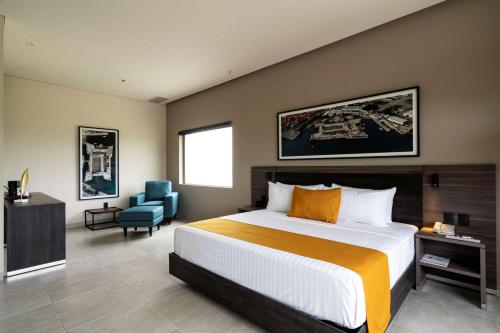a bedroom with a large bed and a blue chair at Best Western Plus Riviera Veracruz in Veracruz