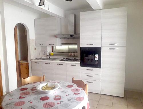 トロペアにあるCasa Vacanze Calabriaのテーブル付きのキッチン、白いキャビネット付きのキッチン