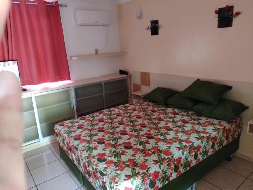 a bedroom with a bed with a floral bedspread at Fiori Caldas Novas - 245 in Caldas Novas