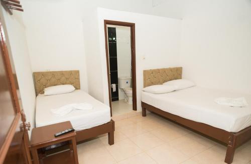 2 camas en una habitación con espejo en Hotel Clau, en Nuquí