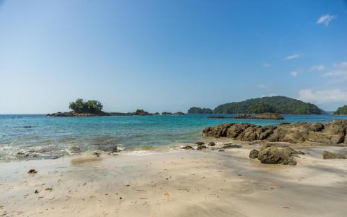 a beach with rocks in the water and a island at Hotel Clau in Nuquí
