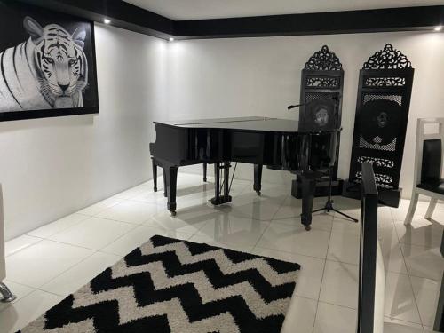 un piano negro en una habitación con una foto de un tigre en Hotel Villa Tournon, en San José