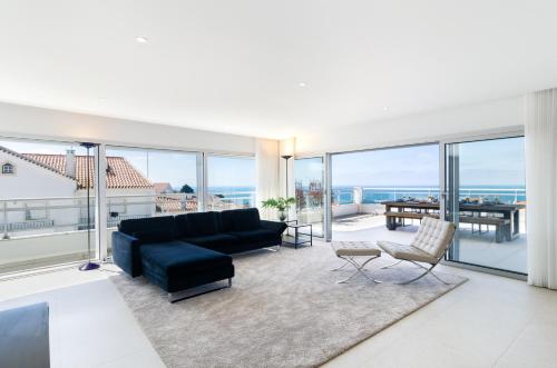 a living room with a black couch and a table at Pico Do Feliz - The Penthouse & The Village By Silver Prop in Nazaré