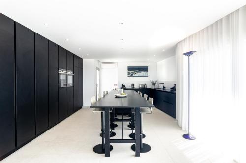 a kitchen with black cabinets and a black table at Pico Do Feliz - The Penthouse & The Village By Silver Prop in Nazaré