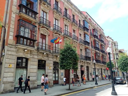 un grupo de personas caminando en una calle frente a un edificio en Hospedaje Don Pelayo, en Gijón
