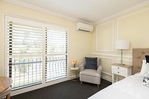 a bedroom with a bed and a chair and a window at Lincoln Downs Resort Batemans Bay in Batemans Bay