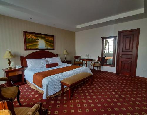 a hotel room with a bed and a table and chairs at Grand Victoria Boutique Hotel in Loja