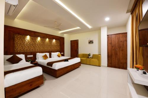 a hotel room with two beds and a couch at Hotel BV Colours Bommanahalli in Bangalore