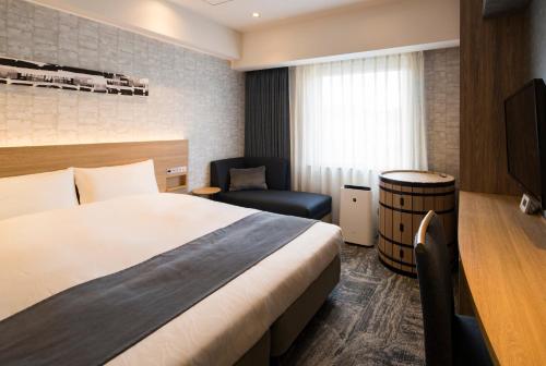 a hotel room with a bed and a chair at Hotel Torifito Otaru Canal in Otaru