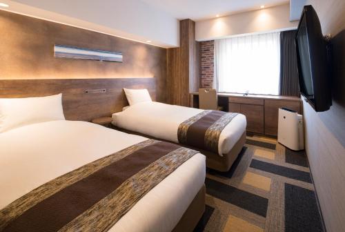 a hotel room with two beds and a flat screen tv at Hotel Torifito Otaru Canal in Otaru