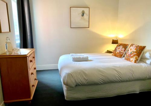 a bedroom with a bed with a dresser and a night stand at The Barkly Bistro Bar & Accommodation in Ararat