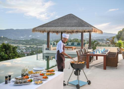 a chef cooking food on a grill on a patio at Baan Kimsacheva - Seaview Private Villa in Choeng Mon Beach