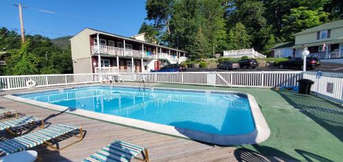 una piscina en una terraza con sillas y un edificio en Pinebrook Motel, en Lake George