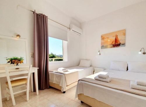 a bedroom with two beds and a desk and a window at Eva Ivoni apartments in Amoudara Herakliou