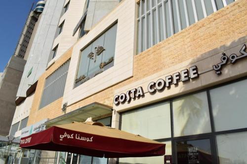 a coffee shop with an umbrella in front of a building at Sedra Residence in Kuwait