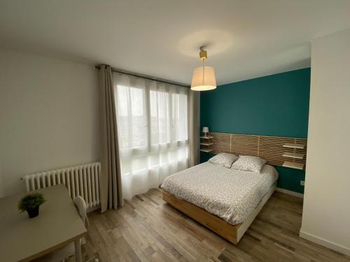 1 dormitorio con cama y pared azul en Le Majestic idéal famille, entreprise, proximité centre, fac Jean monnet, en Saint-Étienne