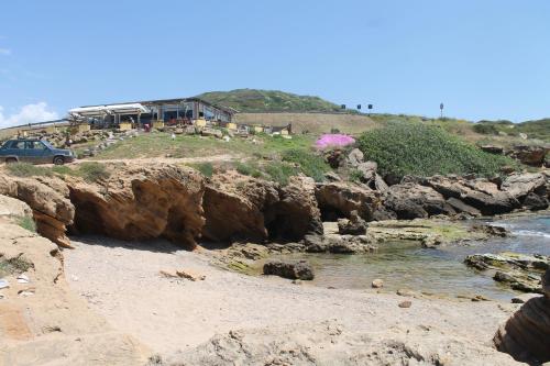 a view of a beach with a building on a hill at Algherooms in Alghero