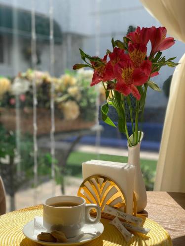 a cup of coffee and a vase with flowers on a table at Guest house TWINS in Tashkent