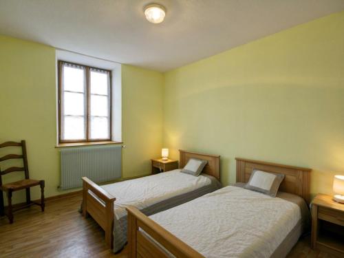 Duas camas num quarto com uma cadeira e uma janela em Gîte La Chambonie, 4 pièces, 6 personnes - FR-1-496-197 em La Chambonie