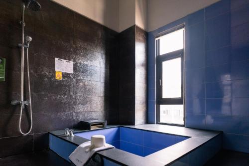 a bathroom with a blue tub and a shower at 58˚ Hotspring Hotel in Jiaoxi