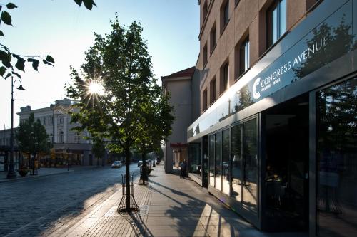 a street with a building and a tree on the sidewalk at Congress Avenue Hotel in Vilnius