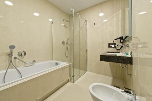a bathroom with a tub and a sink and a shower at Congress Avenue Hotel in Vilnius