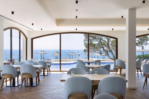 ein Restaurant mit Tischen und Stühlen und Meerblick in der Unterkunft Alua Suites Las Rocas in Cala d´Or