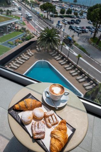 a table with a plate of pastries and a cup of coffee at Lake Front Hotel Mirage in Riva del Garda