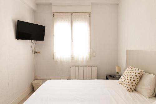 una camera con un letto bianco e una finestra di Pensión Arias a Bilbao