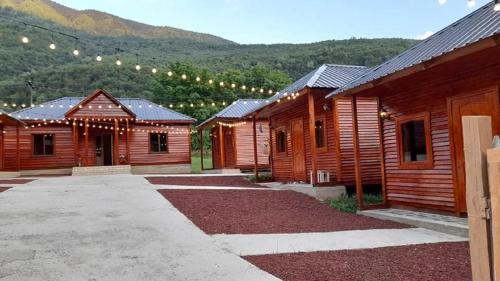 a row of wooden buildings with mountains in the background at Guest House Ushba Gate in Mestia